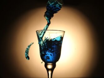 Blau schimmernde Flüssigkeit wird in ein Kelchglas gegossen