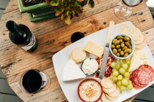 Käseplatte mit Oliven, Trauben, Wurst und Rotwein auf Holztisch