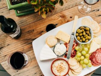 Käseplatte mit Oliven, Trauben, Wurst und Rotwein auf Holztisch