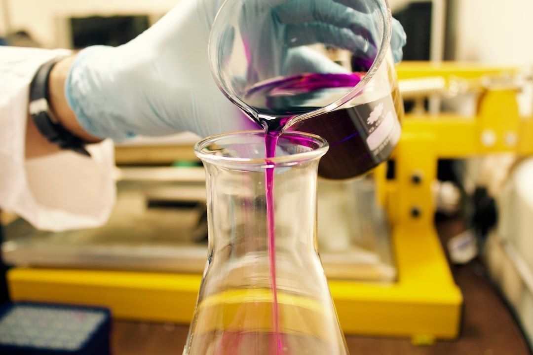 Laborhandschuhe gießen eine violette Flüssigkeit in einen Glaskolben